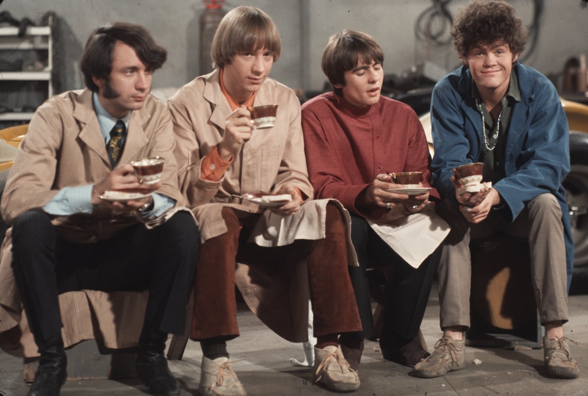 Band members of The Monkees smile while drinking coffee
