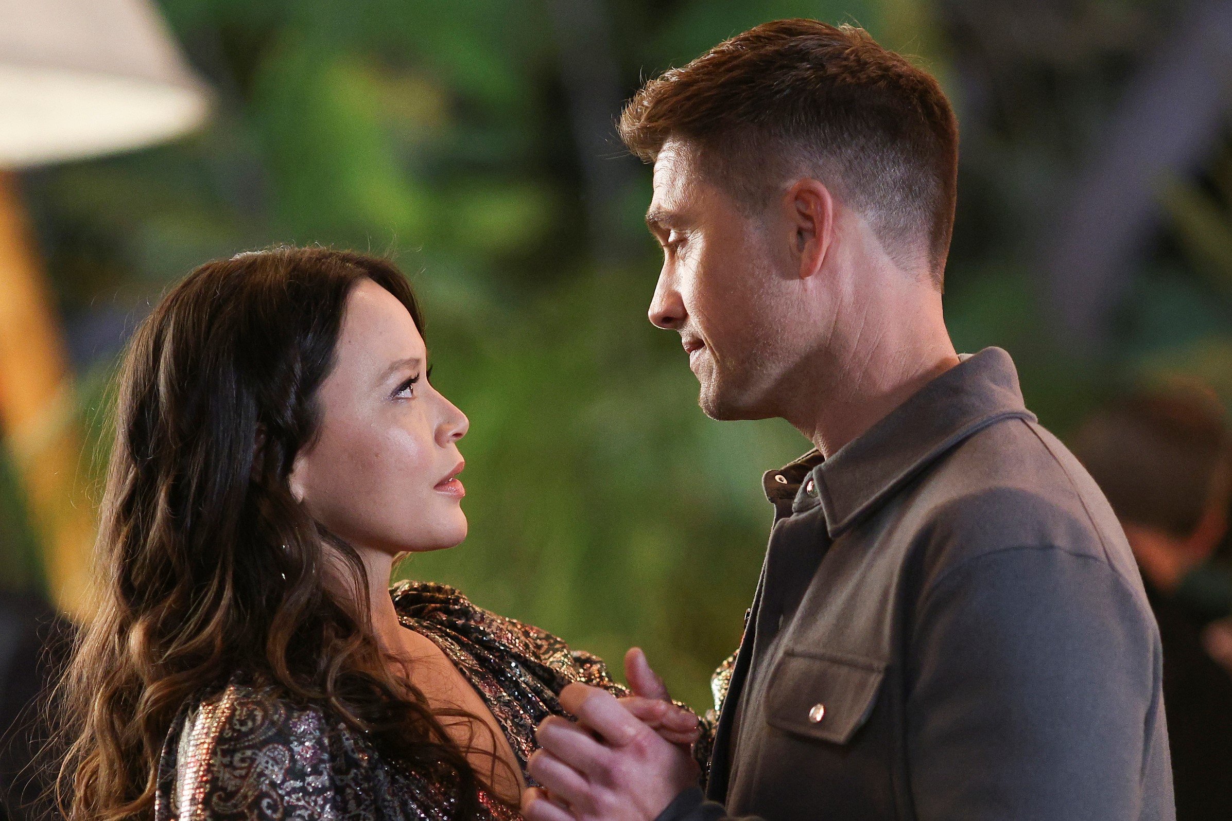 Melissa O'Neil and Eric Winter, in character as Lucy Chen and Tim Bradford in 'The Rookie' Season 4, dance in a scene. Lucy wears a black and gold dress. Tim wears a light gray jacket.