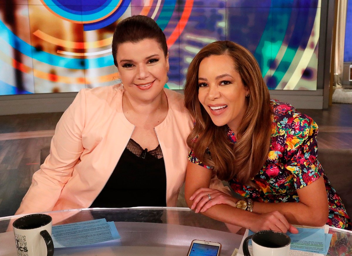 'The View' cohost Ana Navarro in a pink blazer, and Sunny Hostin in a floral dress; post together at the hot topic table.