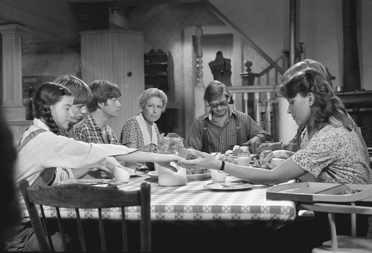Black and white photos of the Waltons sitting around the dining table and holding hands