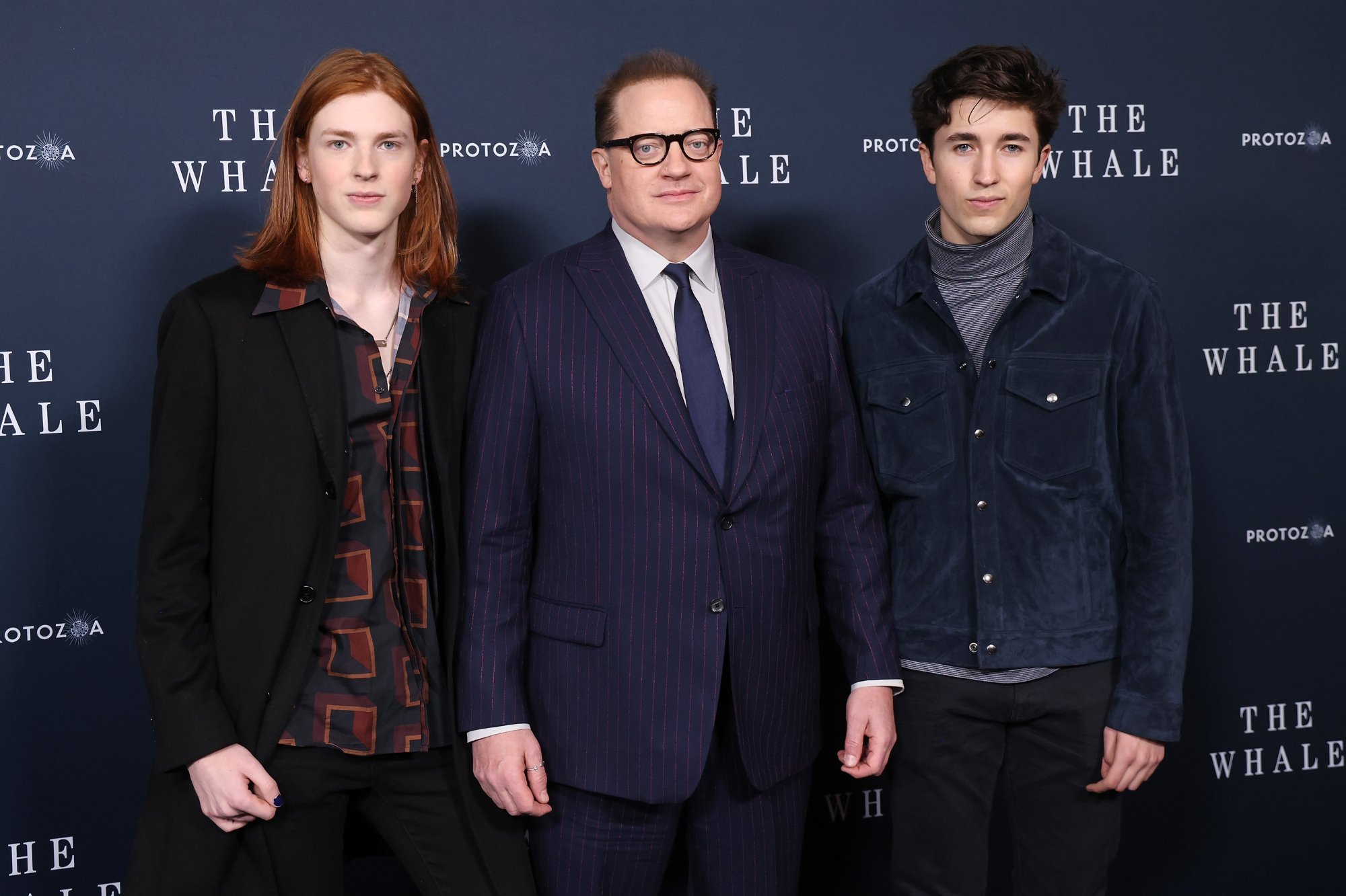 'The Whale' Leland Fraser, Brendan Fraser, and Holden Fraser standing in front of the movie step and repeat in formal clothing.