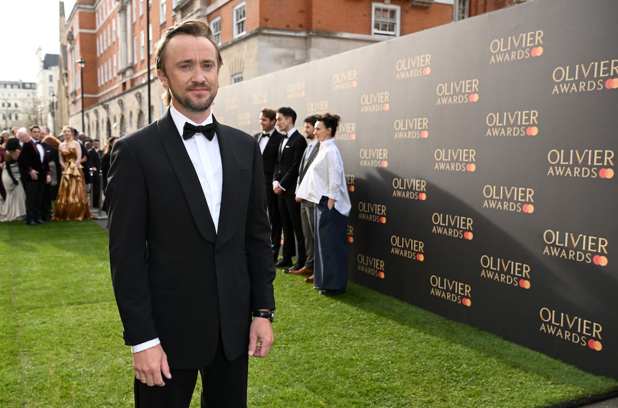 'Beyond the Wand' author Tom Felton stands on a green carpet wearing a tuxedo