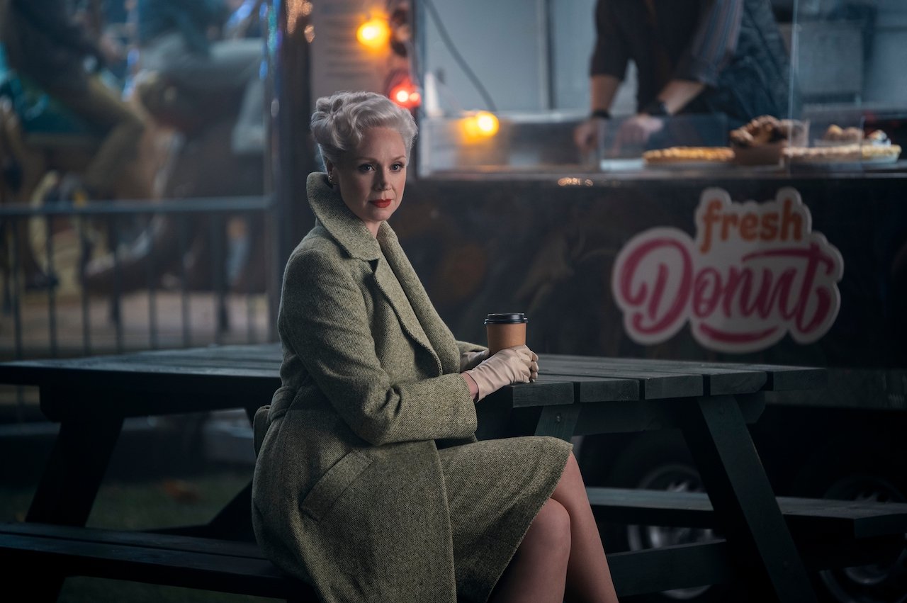 Gwendoline Christie as Larissa Weems sits on a bench in a fair in 'Wednesday'.