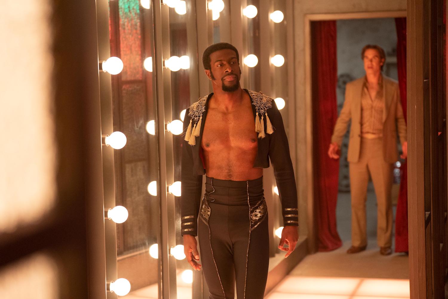 'Welcome to Chippendales' character Otis, played by Quentin Plair, stands in front of mirrors and lights with his shirt unbuttoned.