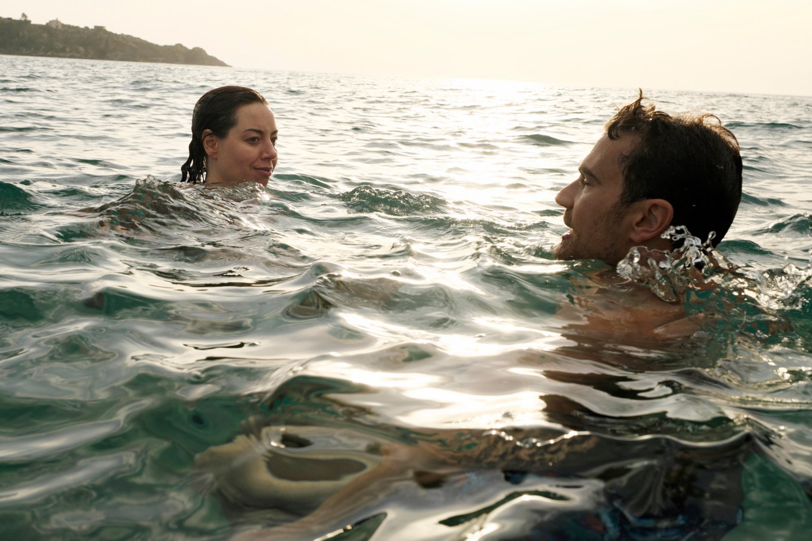 Aubrey Plaza and Theo James in 'The White Lotus' Season 2. They're swimming in the ocean.