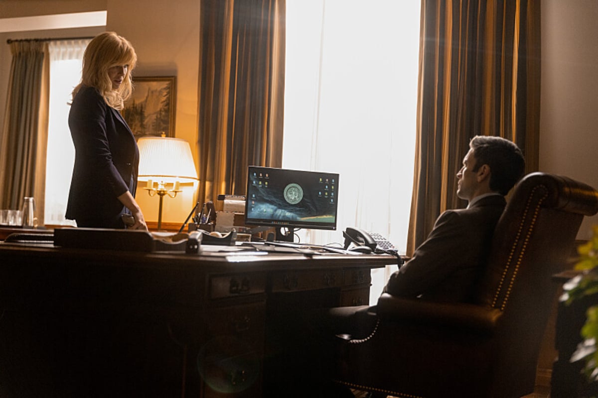 In Yellowstone, Beth and Jamie talk. Beth stands in front of his desk and Jamie sits in a chair.
