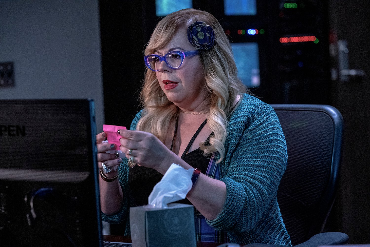 Kirsten Vangsness as Penelope Garcia sitting at her desk and reading her pink Post-It note in Criminal Minds: Evolution
