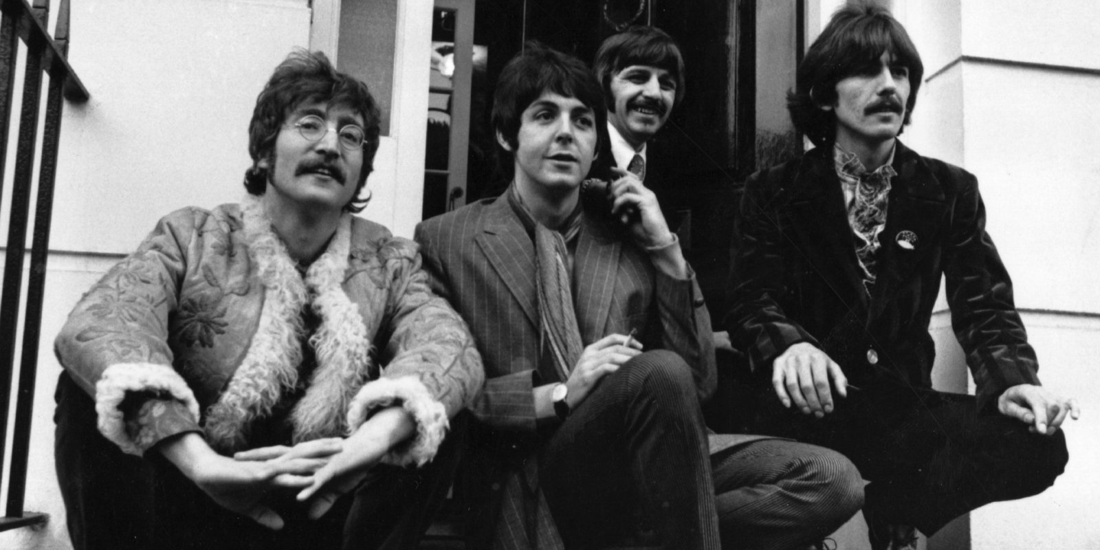 John Lennon, Paul McCartney, Ringo Starr, and George Harrsion sit on the steps of Brian Epstein's house.