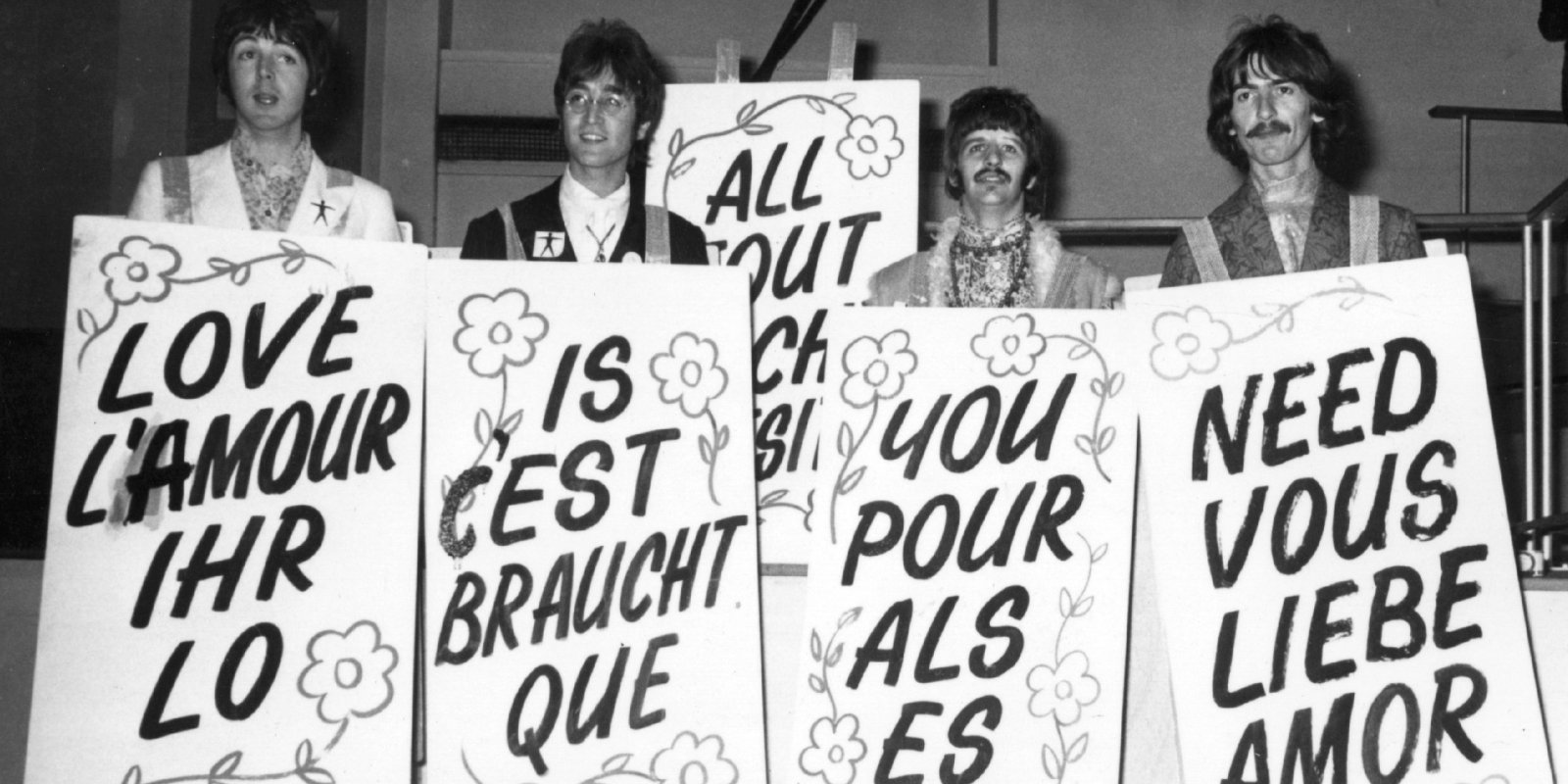 Paul McCartney, John Lennon, Ringo Starr, and George Harrison sporting multi-lingual 'Love Is All You Need' sandwich boards at the EMI studios in Abbey Road, as they prepare for 'Our World.'