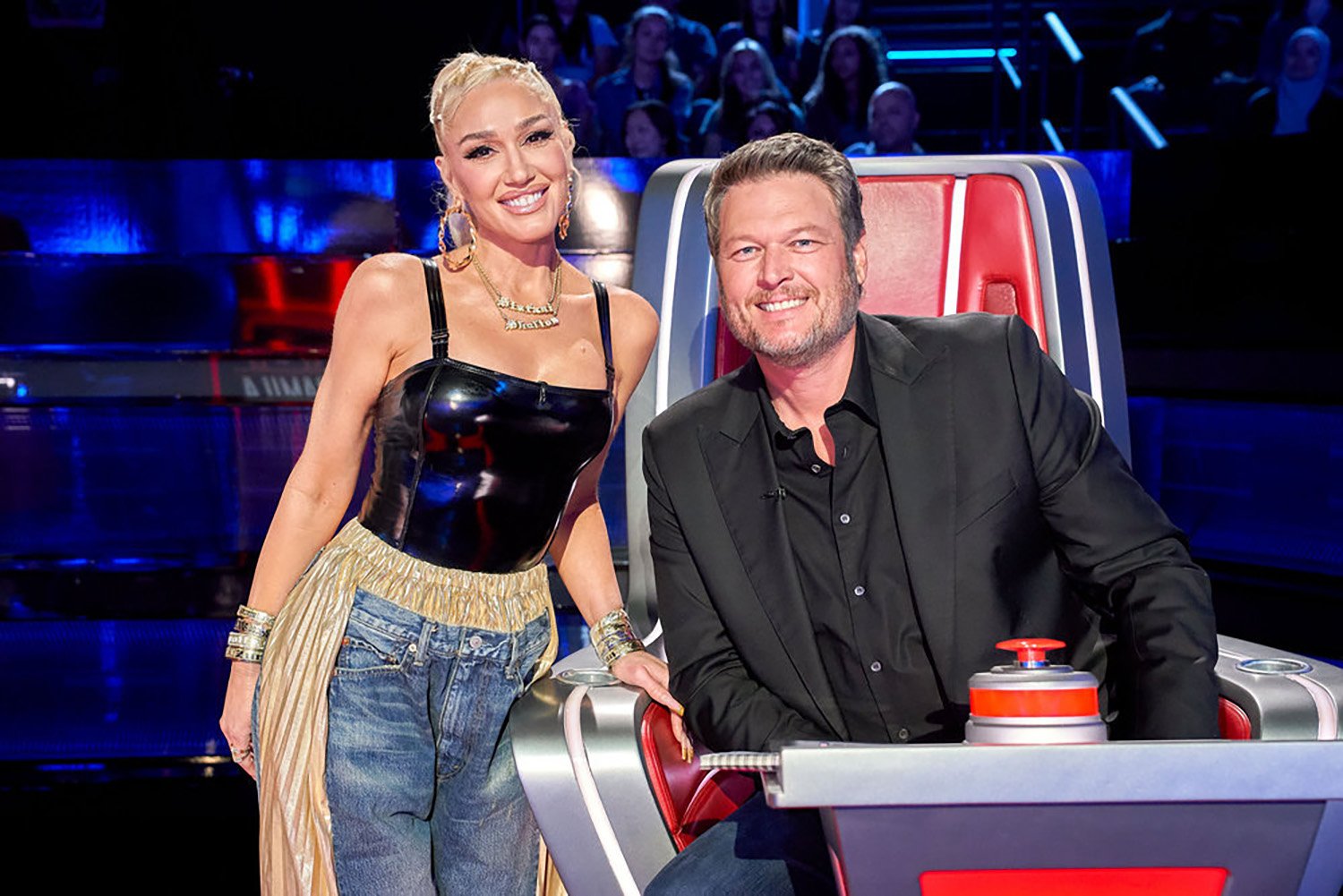 Gwen Stefani poses beside Blake Shelton in his seat on The Voice Season 22