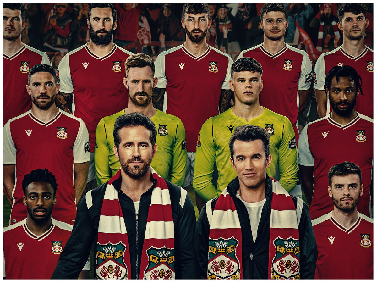 Promotional image for 'Welcome to Wrexham' featuring Ryan Reynolds, Rob McElhenney, and the Wrexham AFC