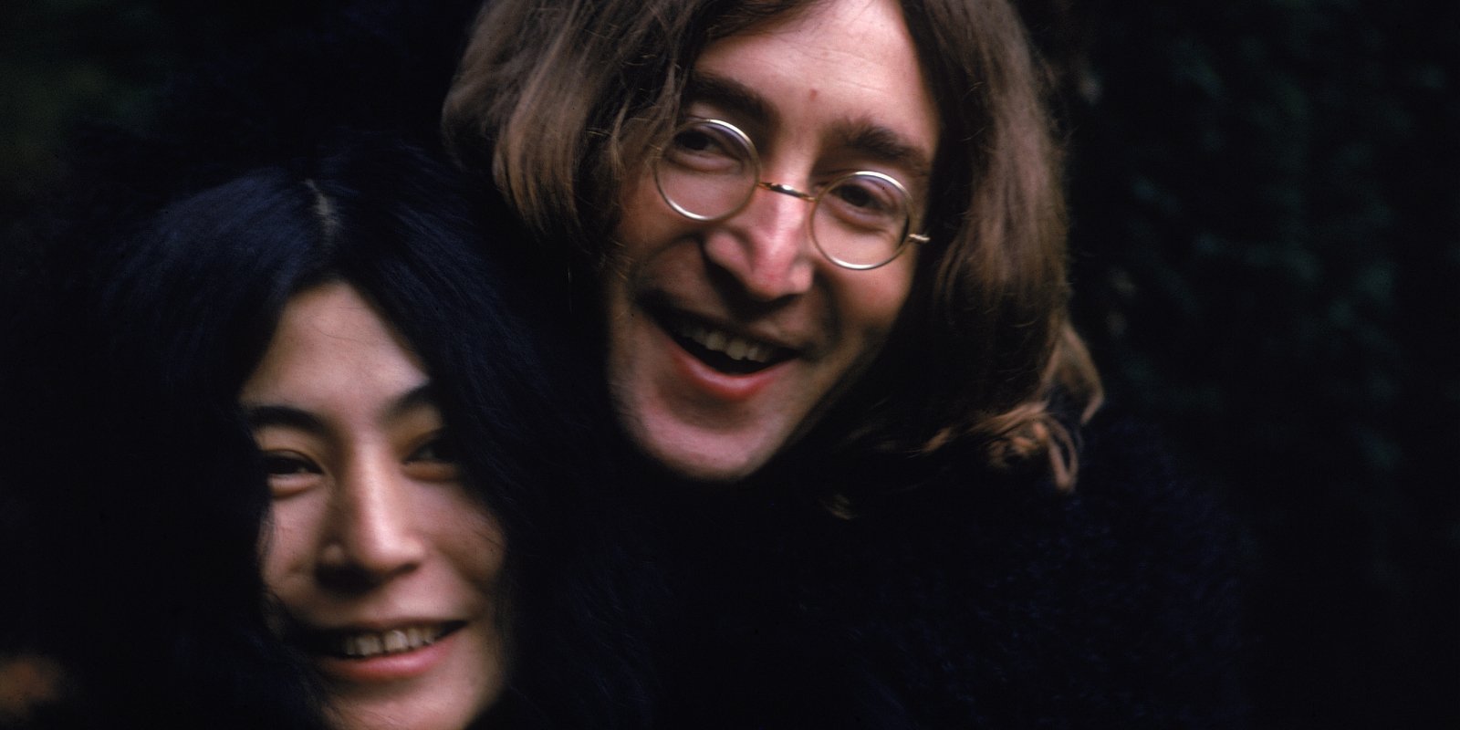 Yoko Ono and John Lennon laughing together in a photograph.