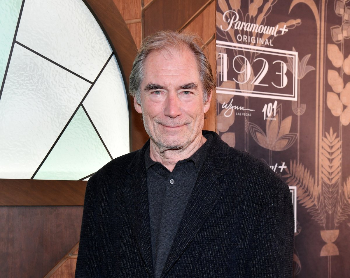 Timothy Dalton discussed the harsh filming conditions for 1923. Dalton attends the 1923 premiere wearing a collared shirt and black suit jacket.