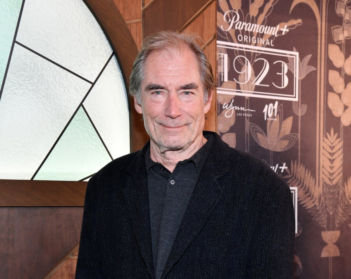 Timothy Dalton discussed the harsh filming conditions for 1923. Dalton attends the 1923 premiere wearing a collared shirt and black suit jacket. 