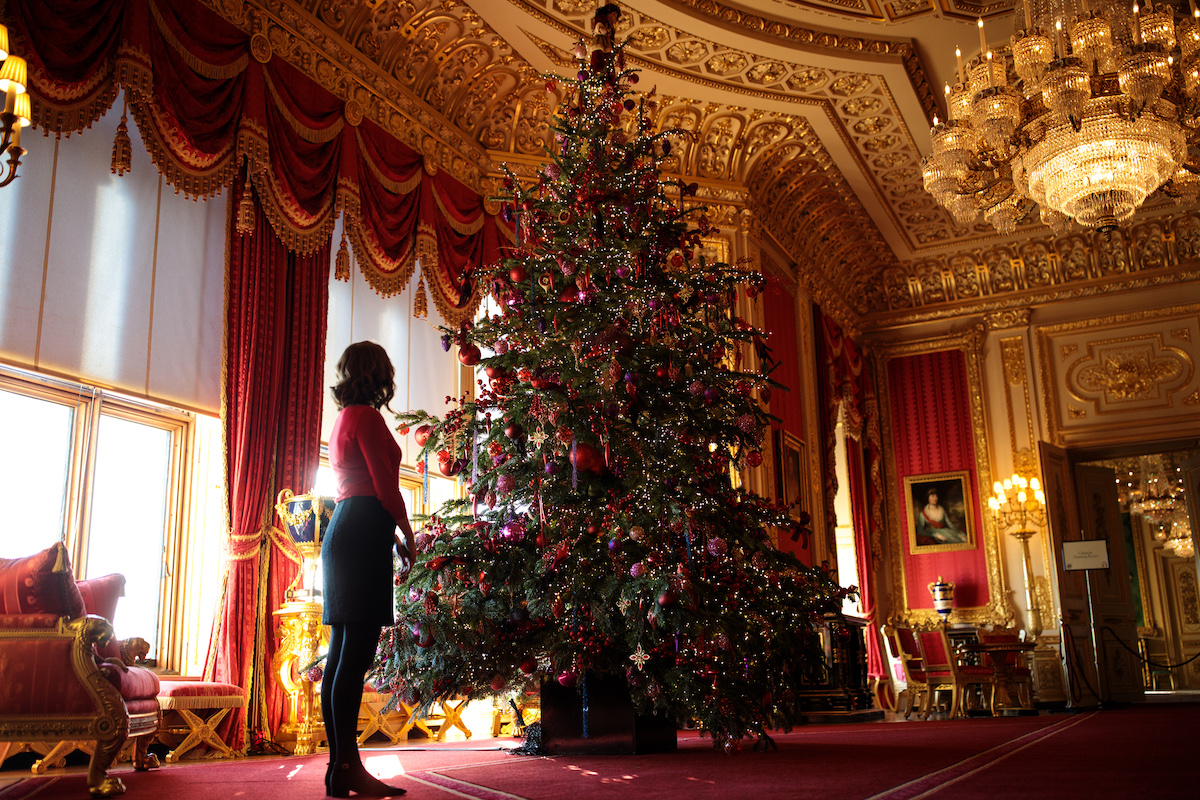 An employee stands next to a Queen Elizabeth Christmas tree at Windsor Castle