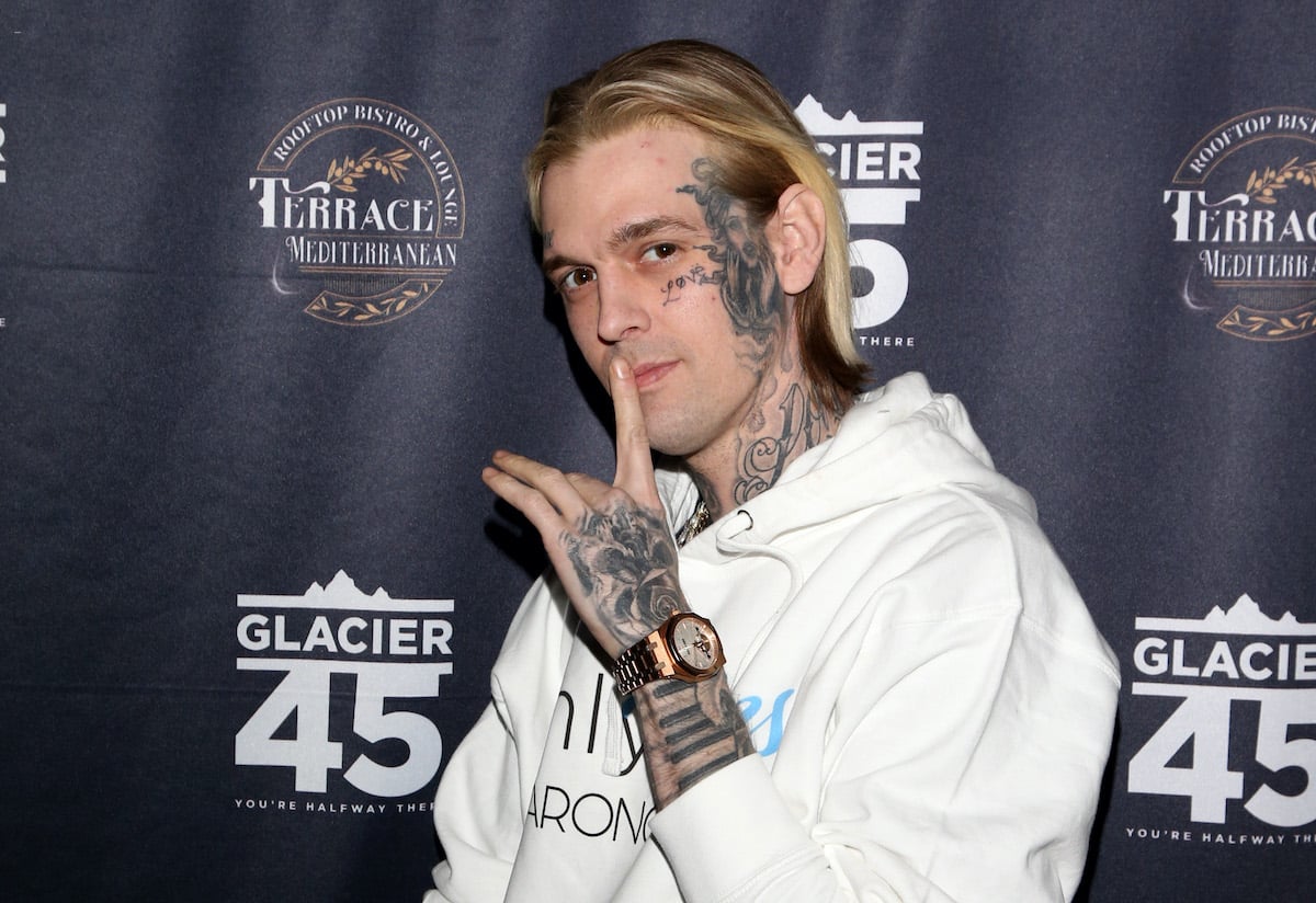 Aaron Carter smiling slightly, holding his finger to his mouth