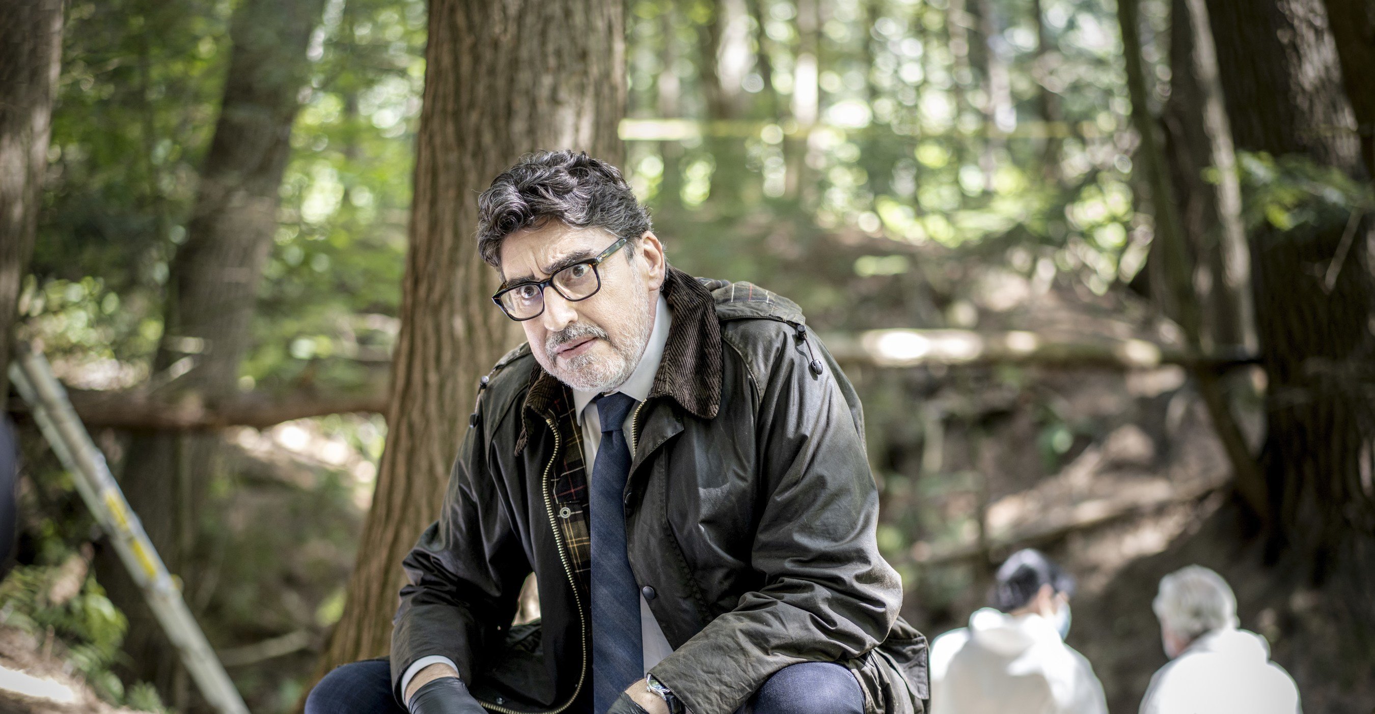 Alfred Molina looking at something on the ground in 'Three Pines'