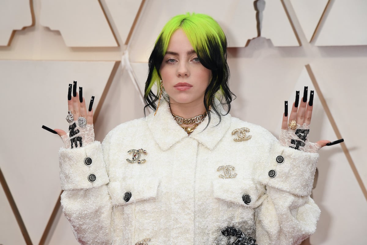 Billie Eilish with green hair in front of a white background