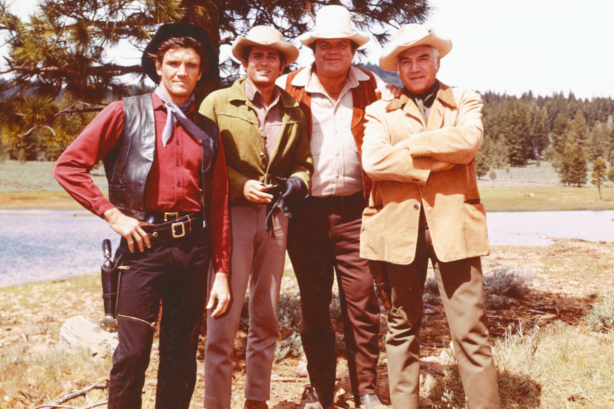 'Bonanza' cast Pernell Roberts, Michael Landon, Dan Blocker, and Lorne Greene wearing Western clothes, standing in the grass in front of a tree