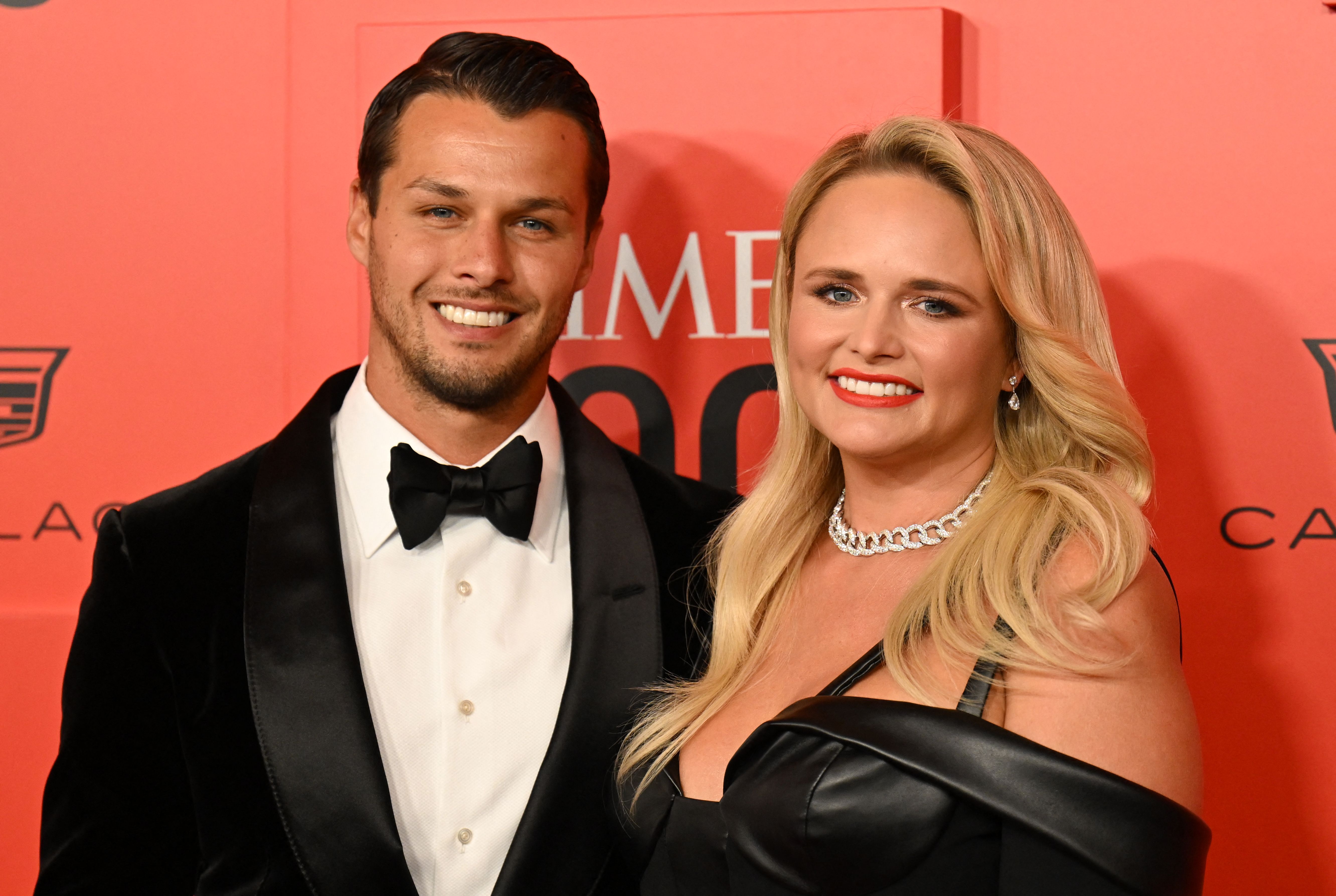 Brendan McLoughlin and Miranda Lambert smile in front of a red backdrop