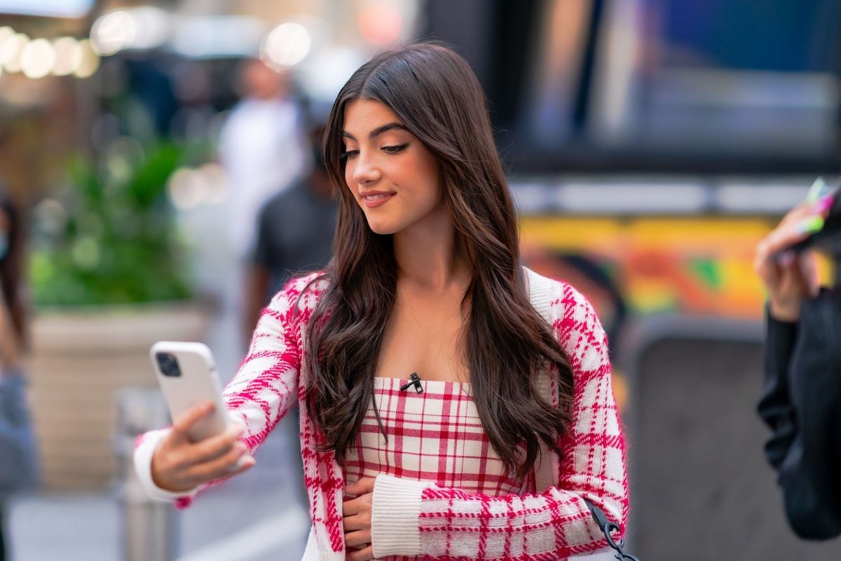 Charli D'Amelio, a nominee for the 2022 Showbiz Social Media Awards, smiles holding a phone 