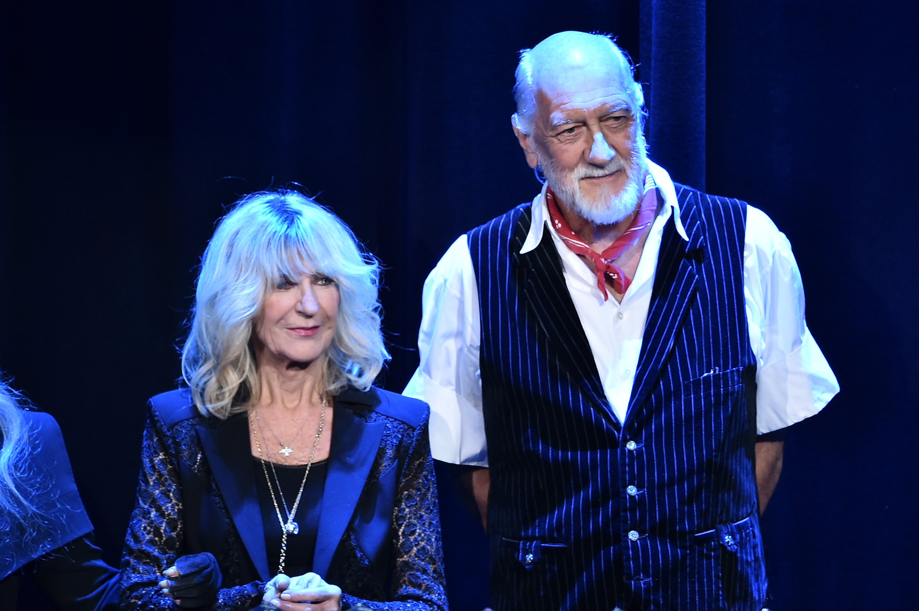 Christine McVie and Mick Fleetwood stand side-by-side in dark blue outfits