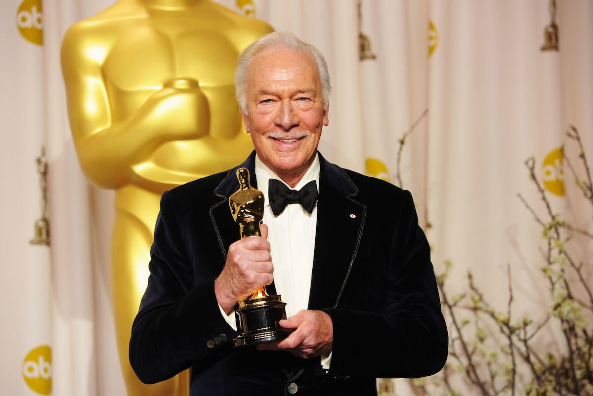 Christopher Plummer smiles while holding an Oscar.