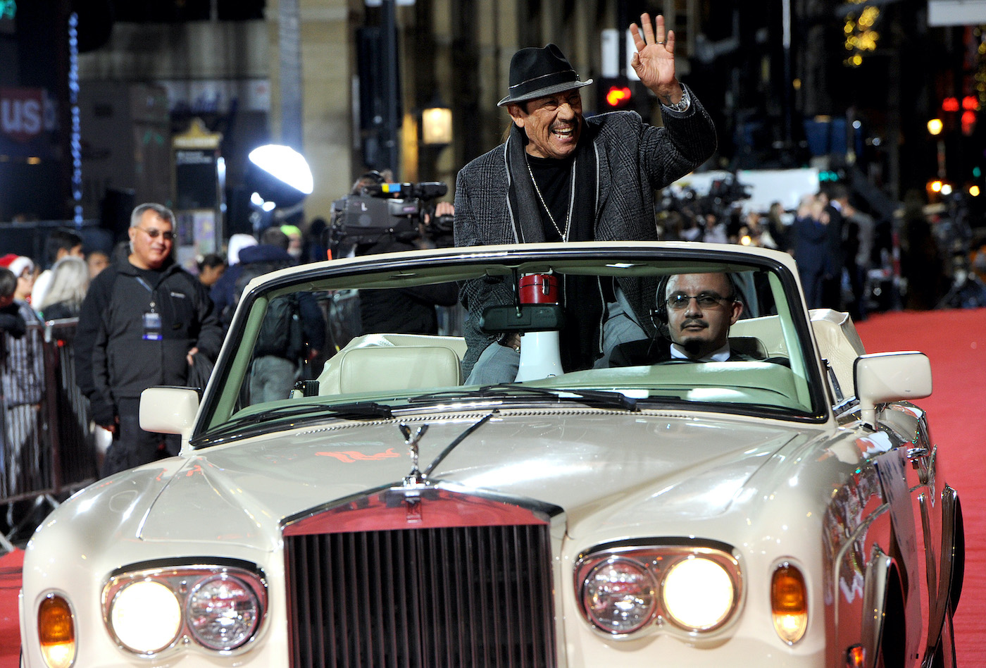 Danny Trejo waves to the crowd from a convertible car in a parade
