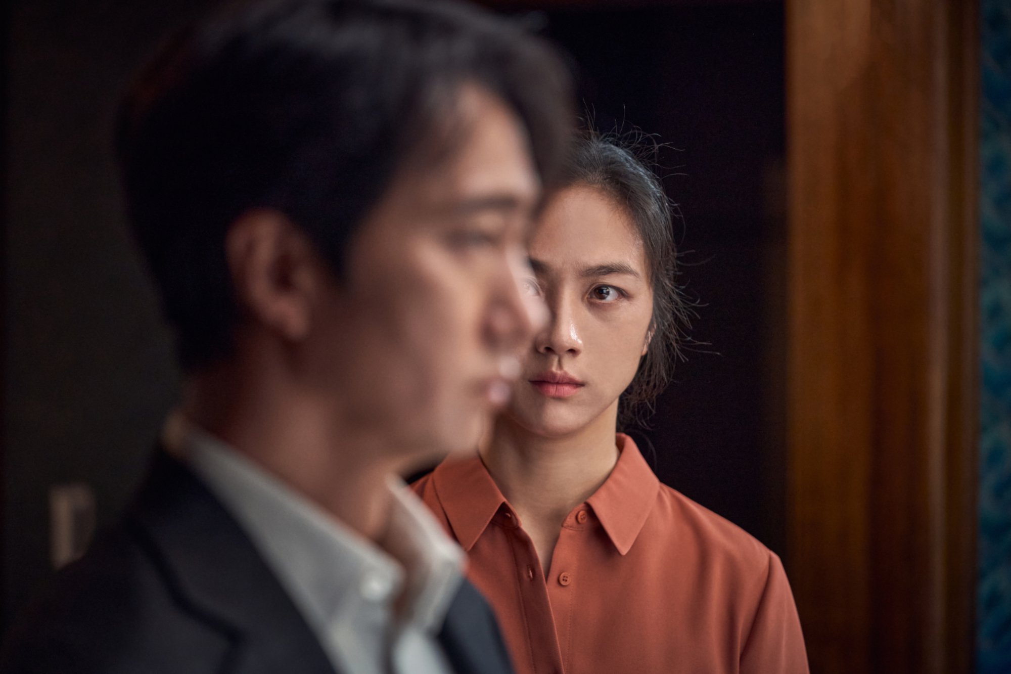 'Decision to Leave' Park Hae-il as Jang Hae-joon and Tang Wei as Song Seo-rae. He's out of focus looking to the side and she's in-focus looking at him.