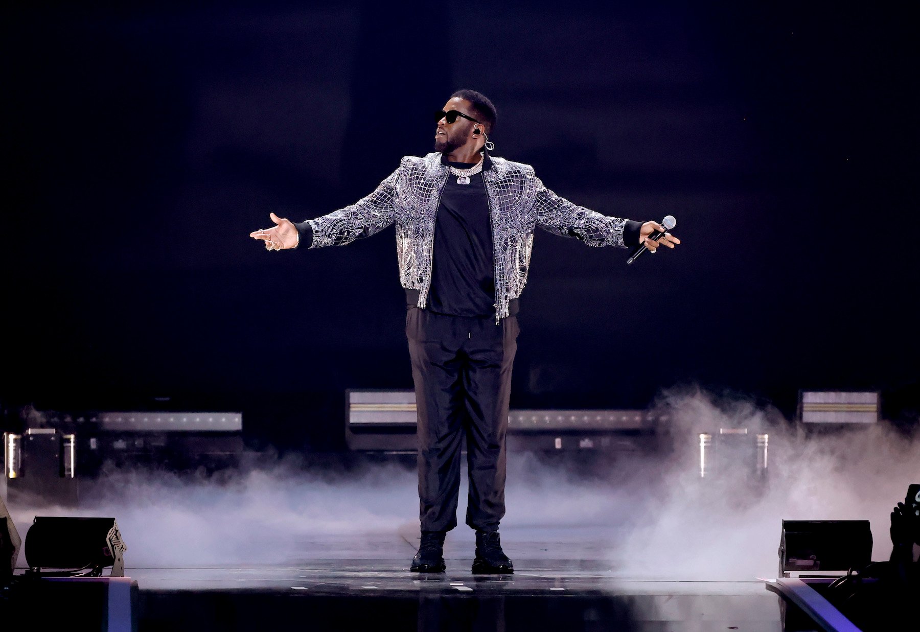 Legacy rapper and record executive Sean “Diddy" Combs on stage wearing a silver jacket and black pants