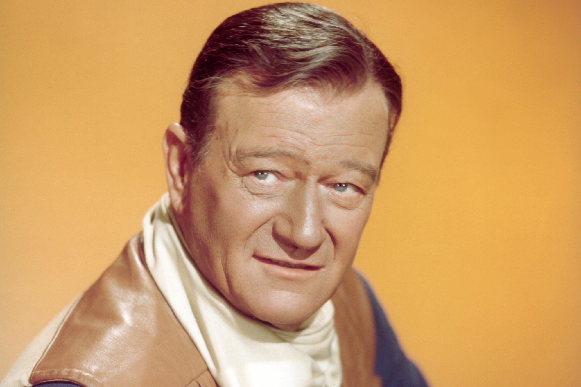 'El Dorado' actor John Wayne in a promo photo with a Western costume in front of a yellow background