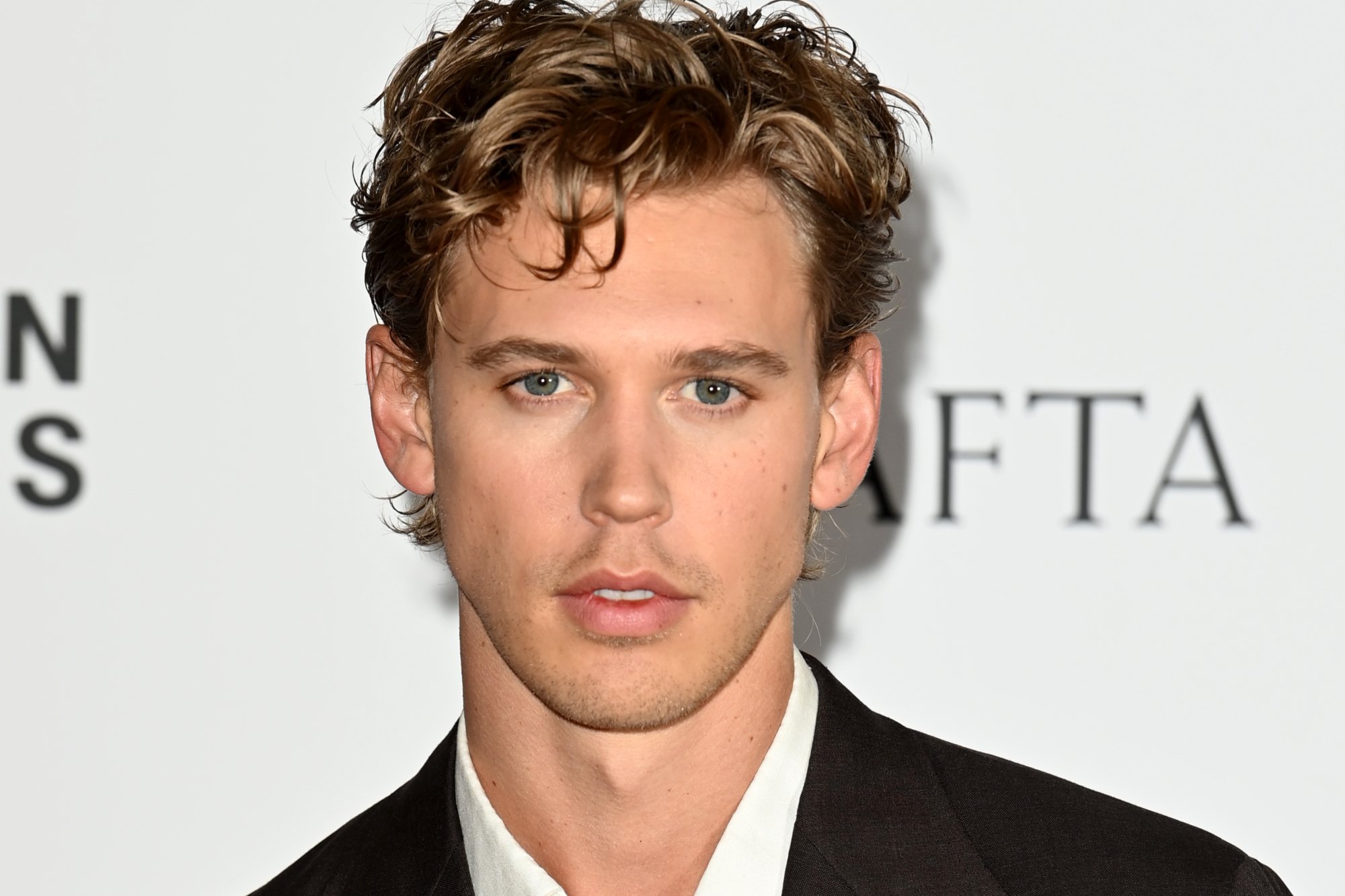 'Elvis' actor Austin Butler posing in front of a white step and repeat