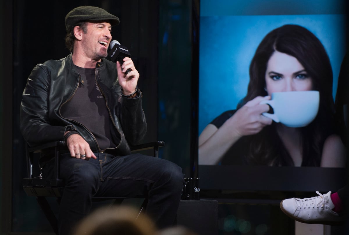 'Gilmore Girls' Luke actor Scott Patterson speaks into a micorphone next to a photo of Lorelai (Lauren Graham) sipping coffee