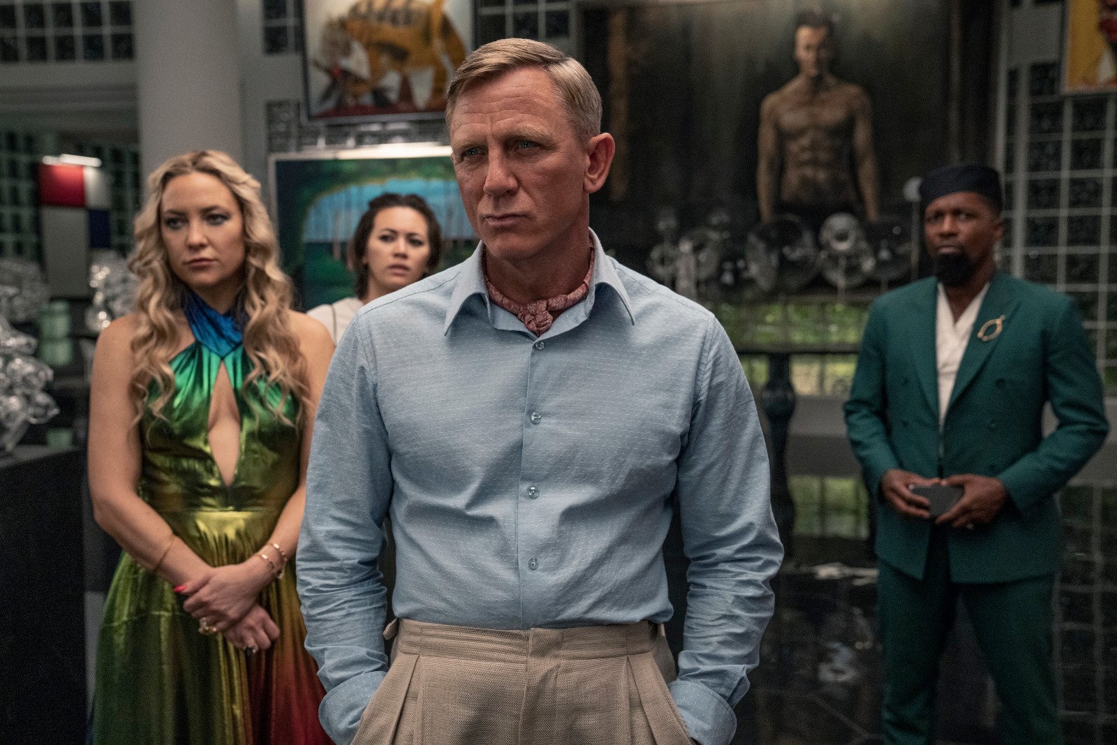 Kate Hudson, Jessica Henwick, Daniel Craig, and Leslie Odom Jr. in 'Glass Onion' for our article covering its ending. Craig is standing in front of the others, and they're staring at someone off-screen.