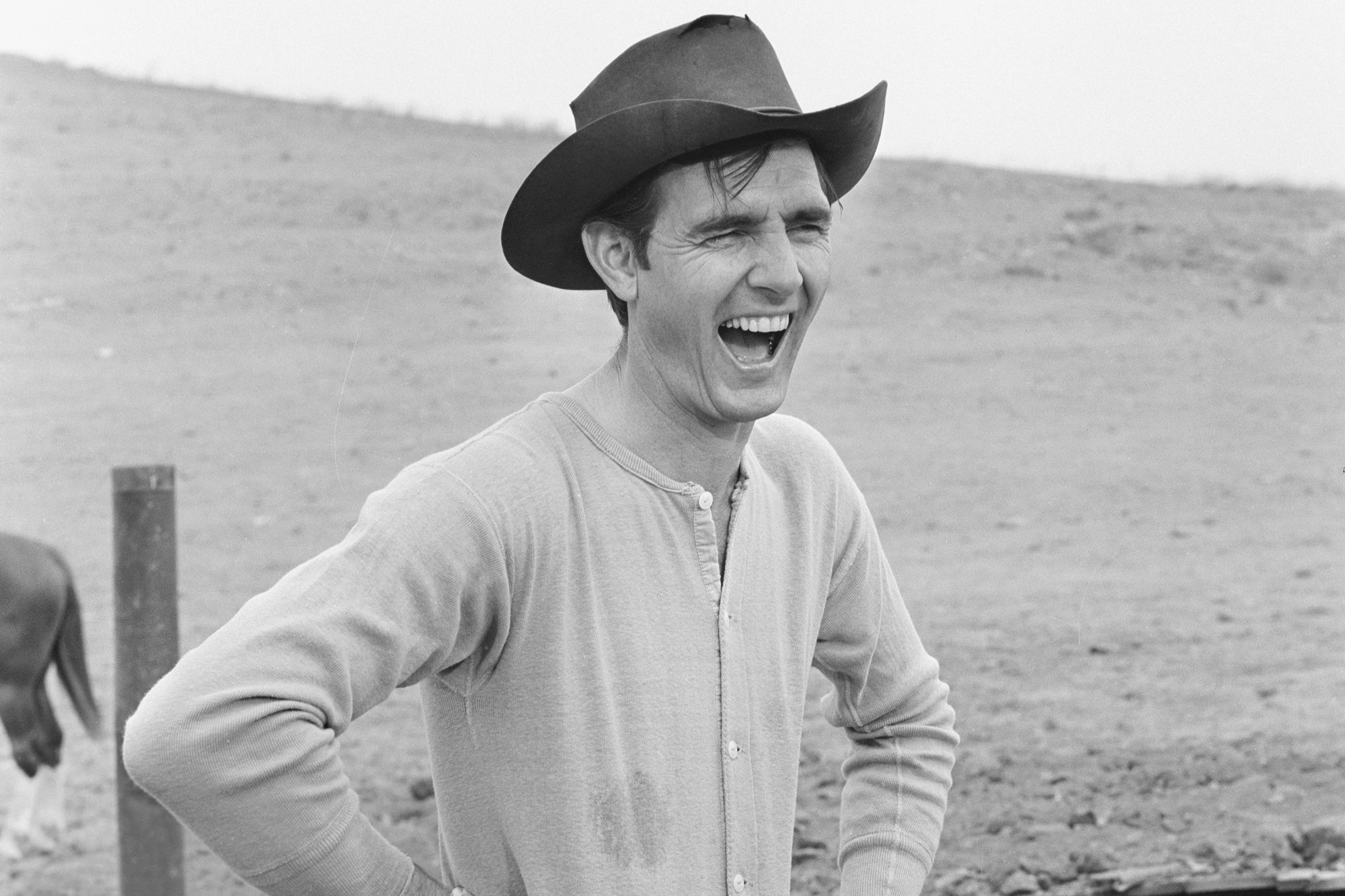 'Gunsmoke' Dennis Weaver as Chester Goode with his hands on his hips, laughing. He's wearing a cowboy hat.