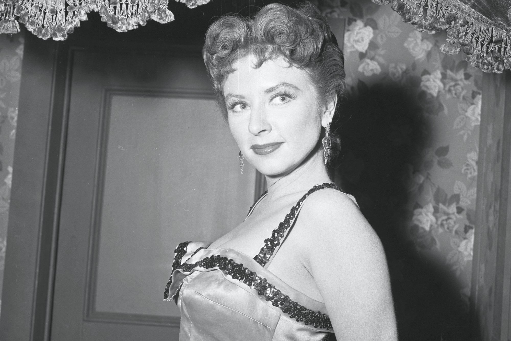 'Gunsmoke' actor Amanda Blake as Miss Kitty Russell leaning back in a satin dress with a smile on her face