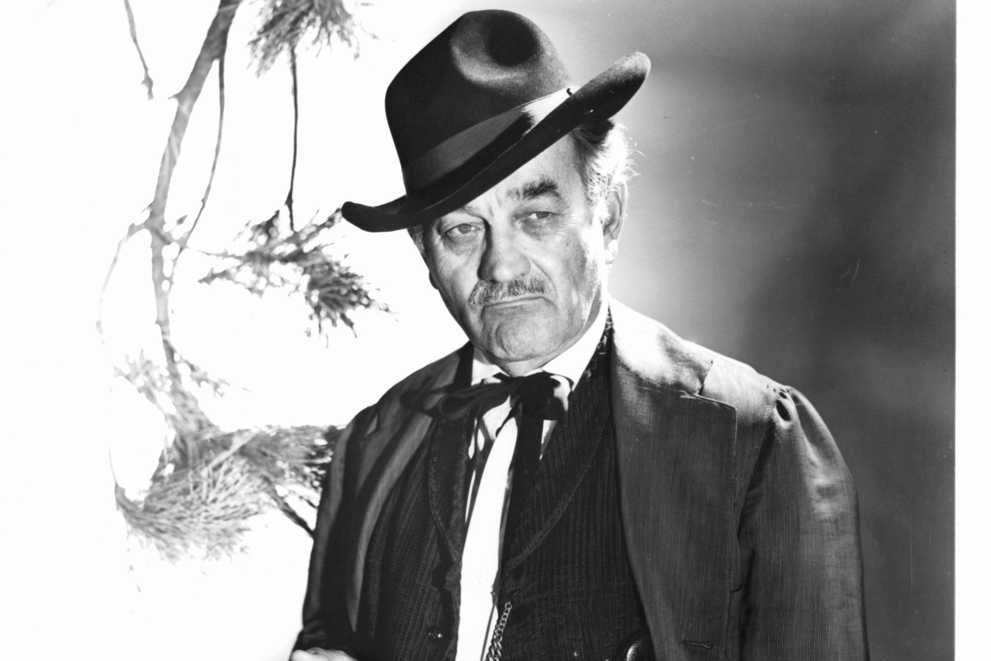 'Gunsmoke' actor Milburn Stone in a black-and-white picture with a plain expression on his face wearing Western clothing