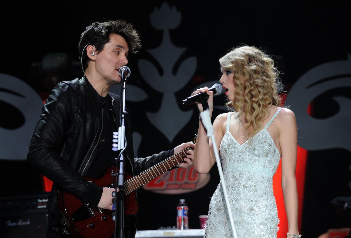 John Mayer and Taylor Swift, who once dated and collaborated on a hit song, sing into microphones on stage together.