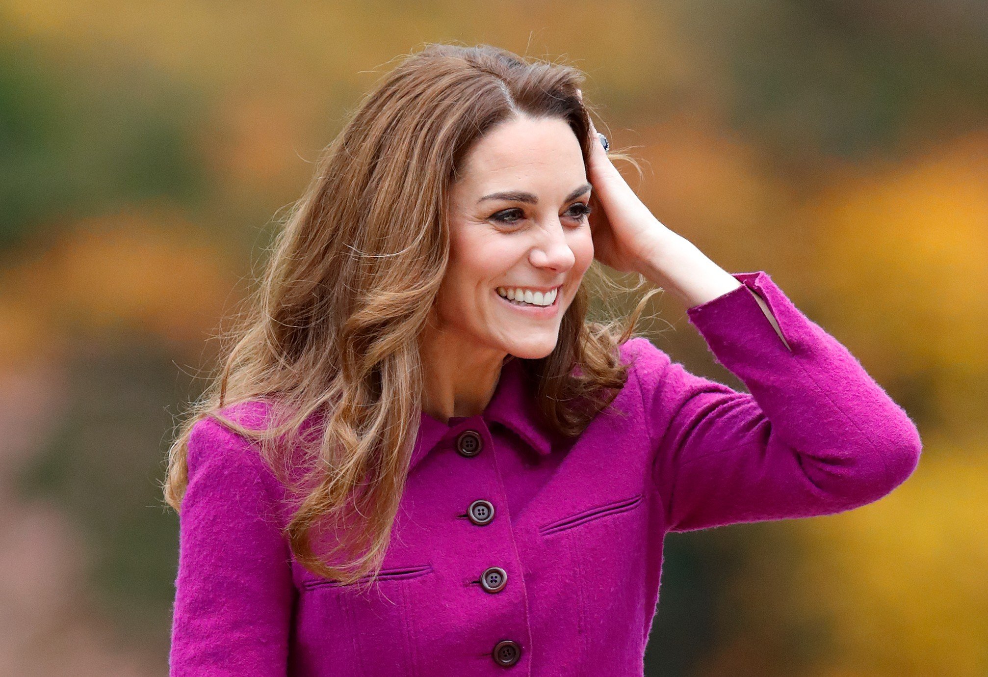 Kate Middleton touches her hair and smiles during an event at 'The Nook' Children's Hospice. 