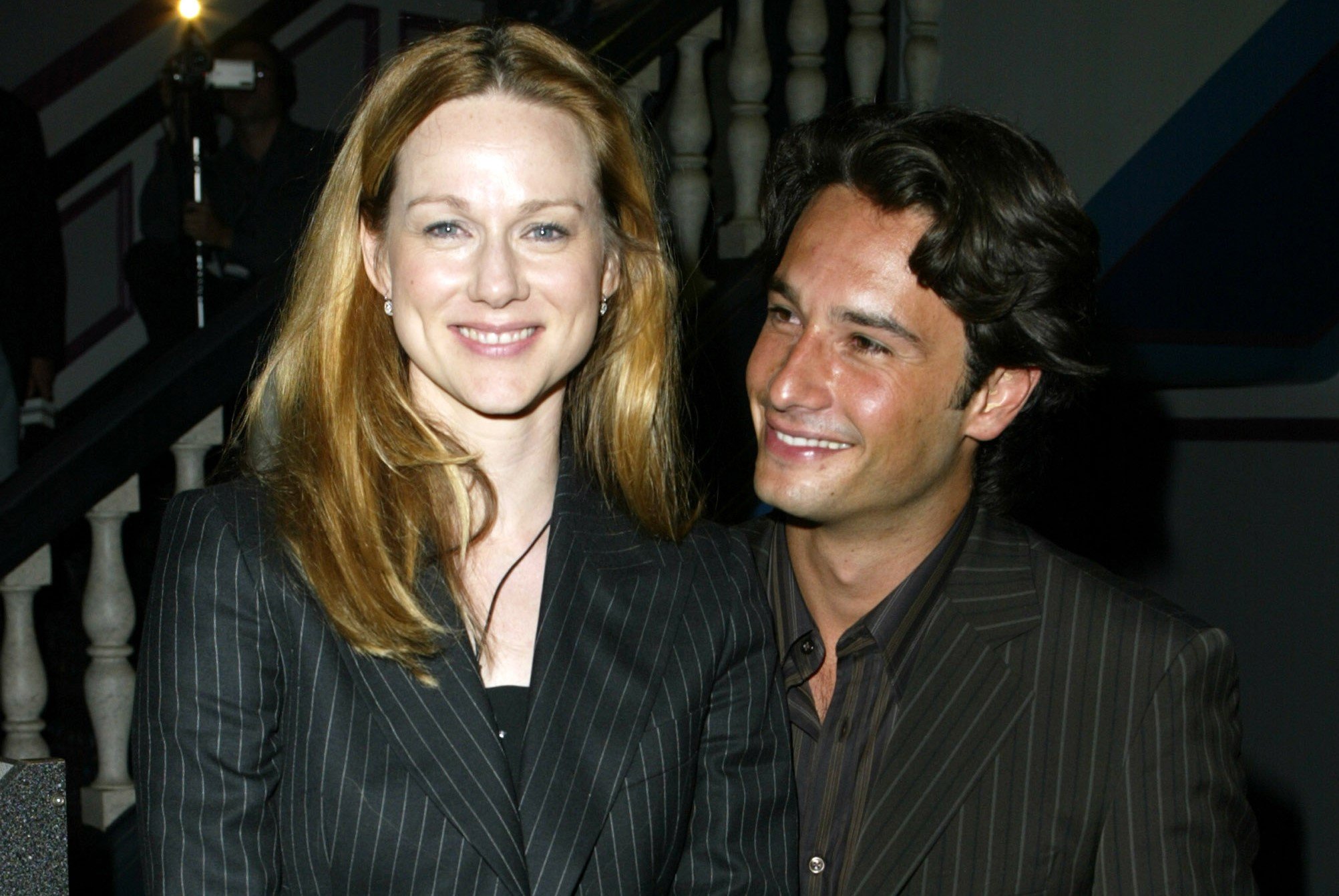 Laura Linney, who appeared in the 'Love Actually' sequel, poses for pictures with Rodrigo Santoro. They wear black suits with thin vertical white stripes.