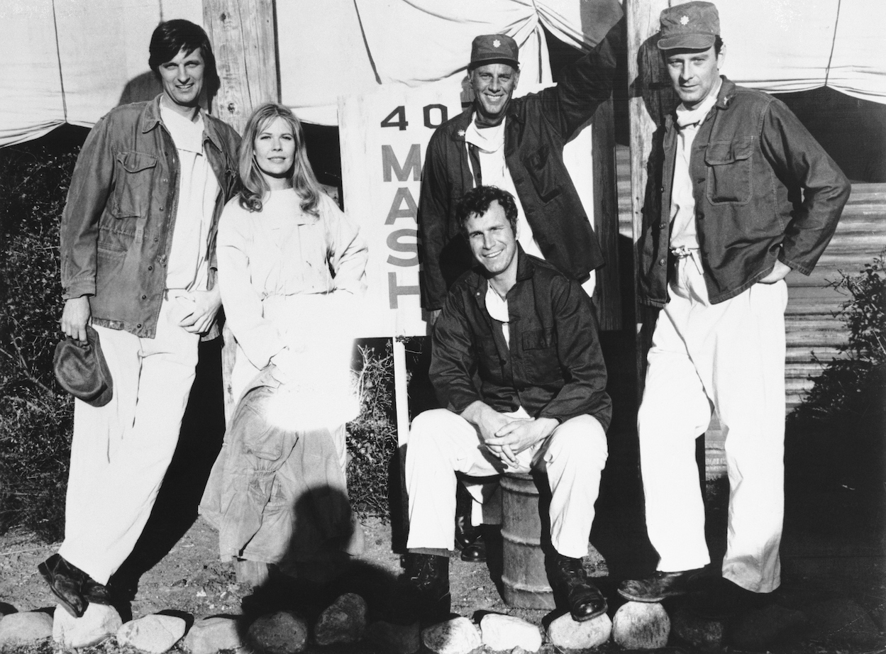A black and white photo of Alan Alda Loretta Swit, Mike Farrell (seated), McLean Stevenson and Larry Linville from 'M*A*S*H'