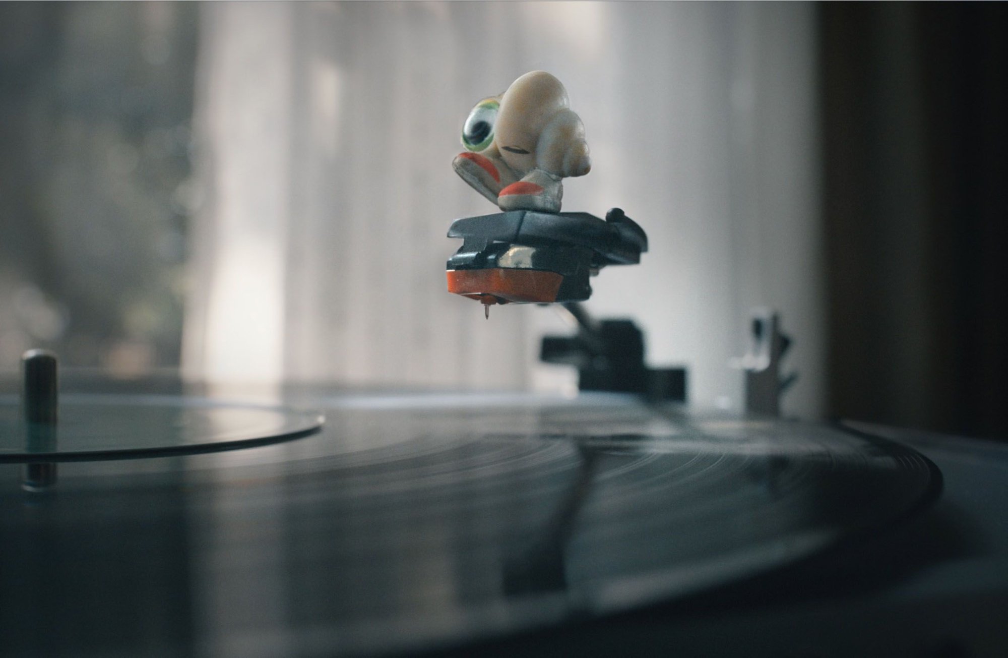 'Marcel the Shell with Shoes On' Marcel voiced by Jenny Slate standing on top of the needle of a record player