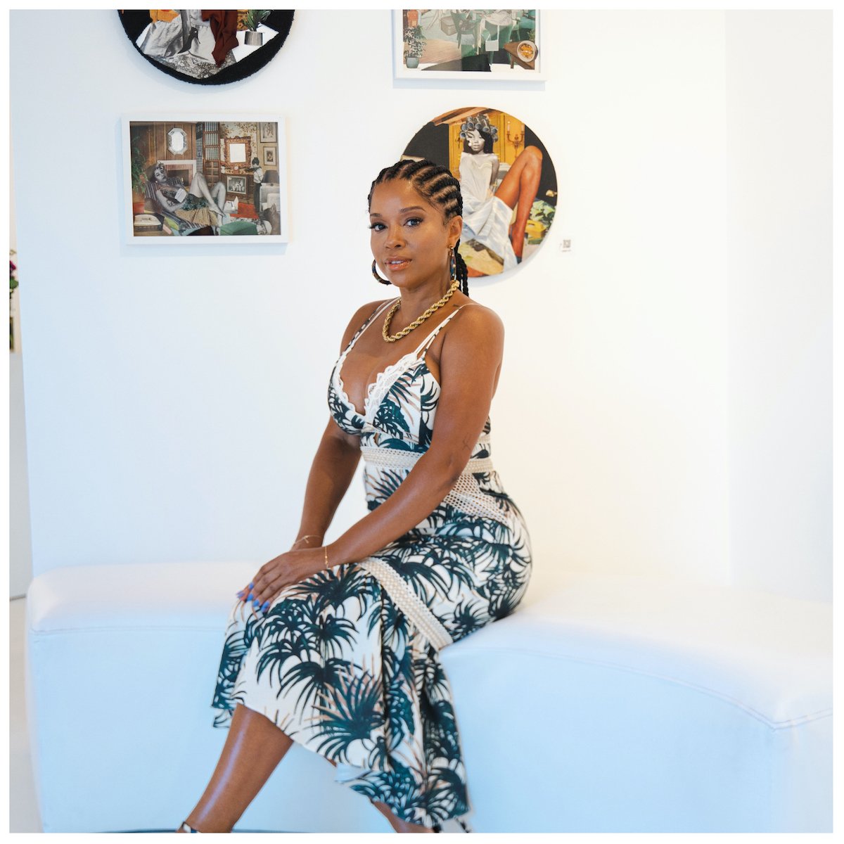 Mashonda sits in front of artwork on the wall 