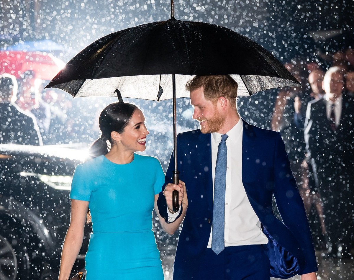 Meghan Markle and Prince Harry smiling in the rain as they attend The Endeavour Fund Awards together