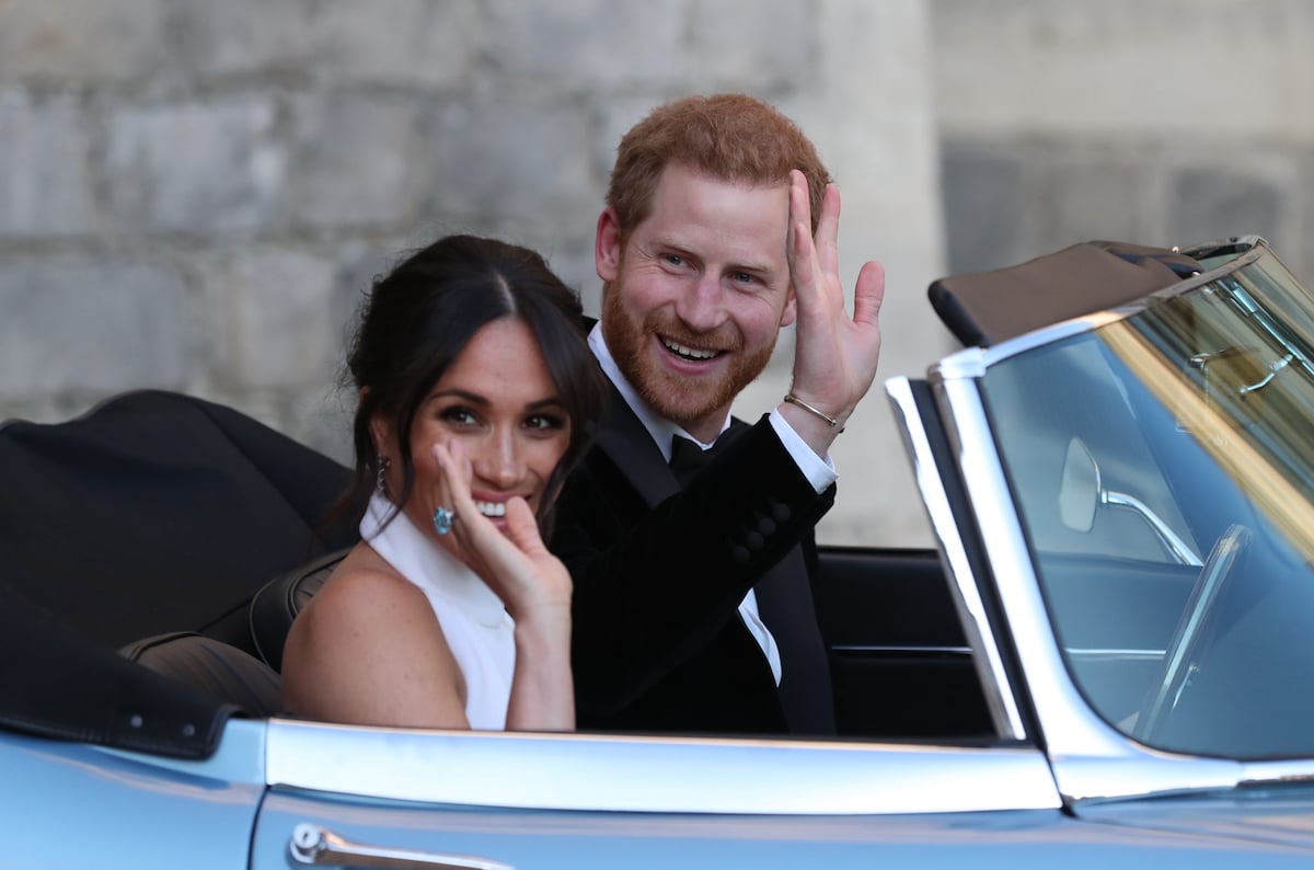 Meghan Markle and Prince Harry, who released an unseen photo of their 2018 royal wedding reception at Frogmore House for the 2018 Christmas card, wave as they drive to Frogmore House