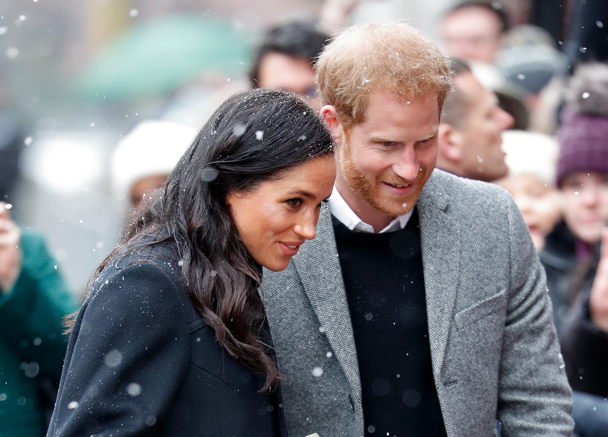 Meghan Markle and Prince Harry watch as they greet the crowd in the snow after spending a week in Norway on New Year's Day 2017.