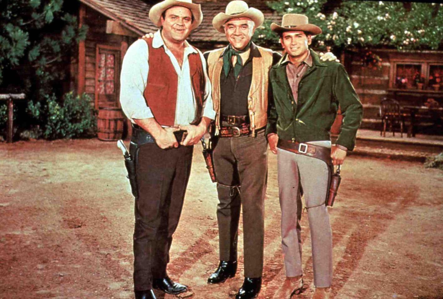 Dan Blocker, Lorne Greene, and Michael Landon in Western clothing standing together in 'Bonanza'