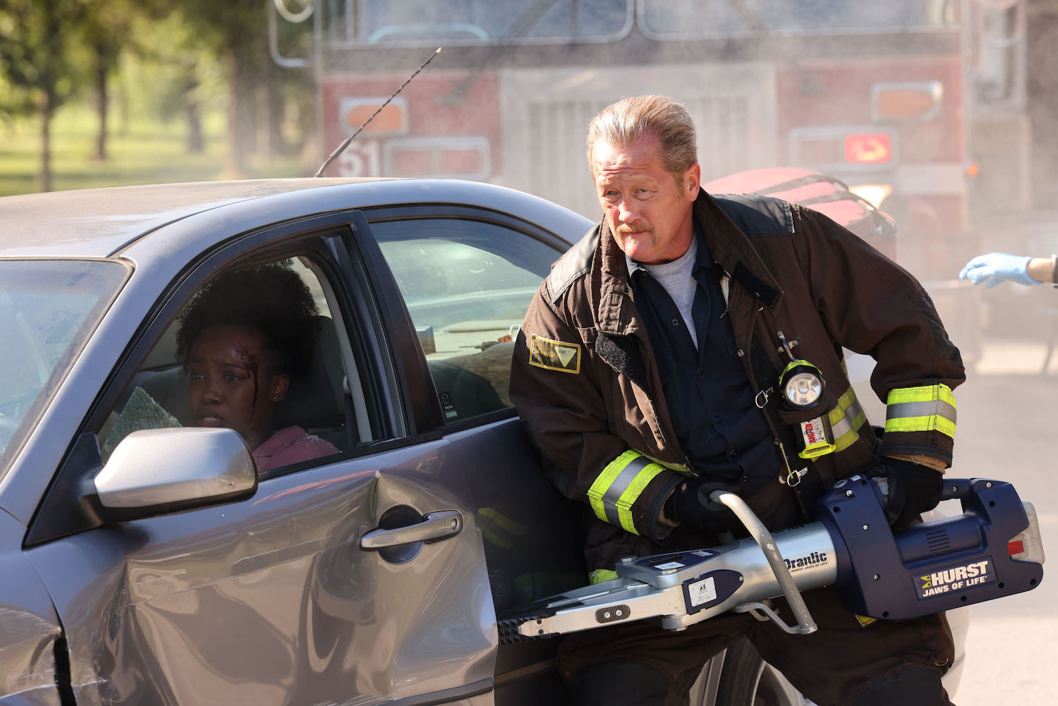 Mouch leaning against a car in 'Chicago Fire' Season 11