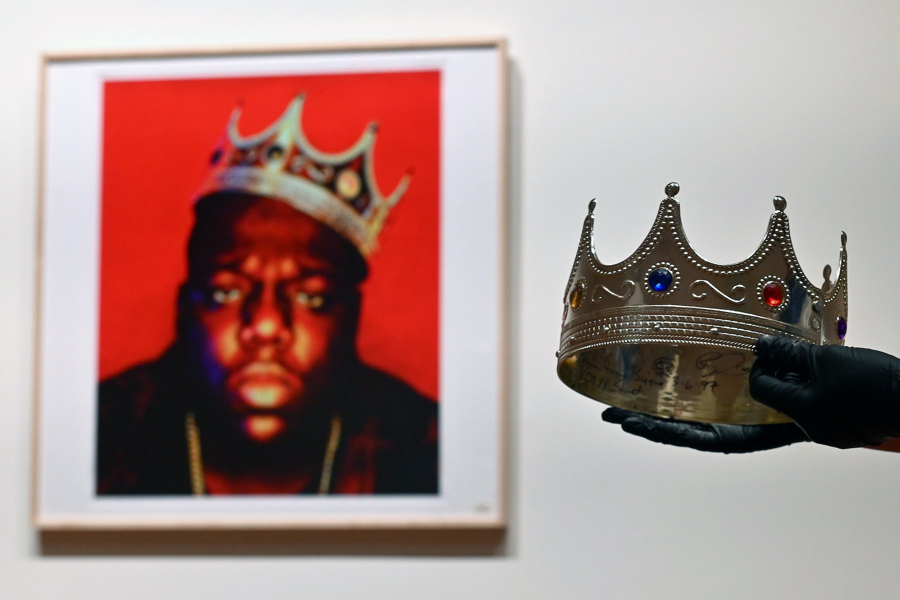 A portrait of The Notorious B.I.G. wearing a crown, next to the actual crown