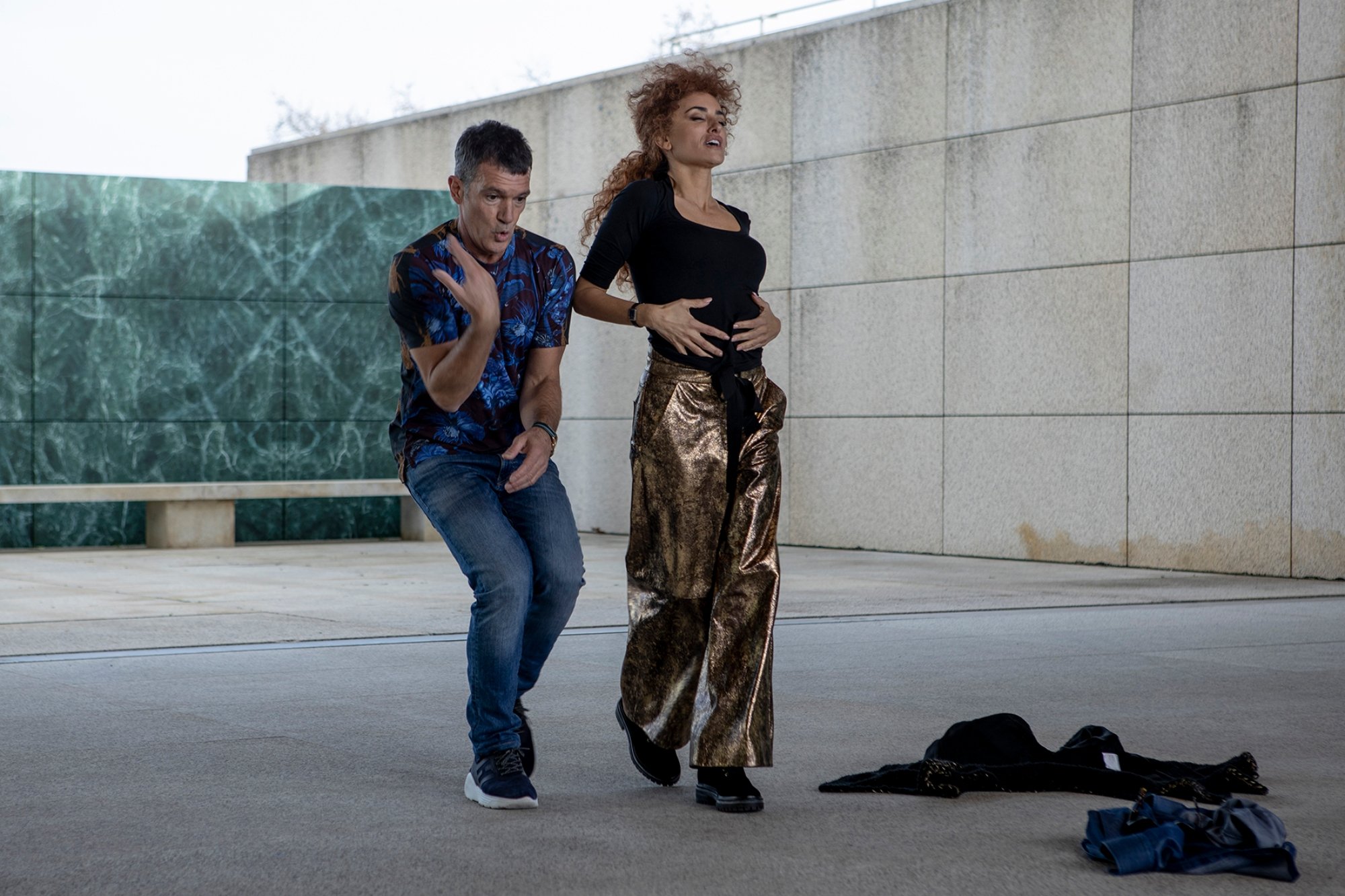 'Official Competition' Antonio Banderas as Félix Rivero and Penélope Cruz as Lola Cuevas dancing next to each other outside of a large building